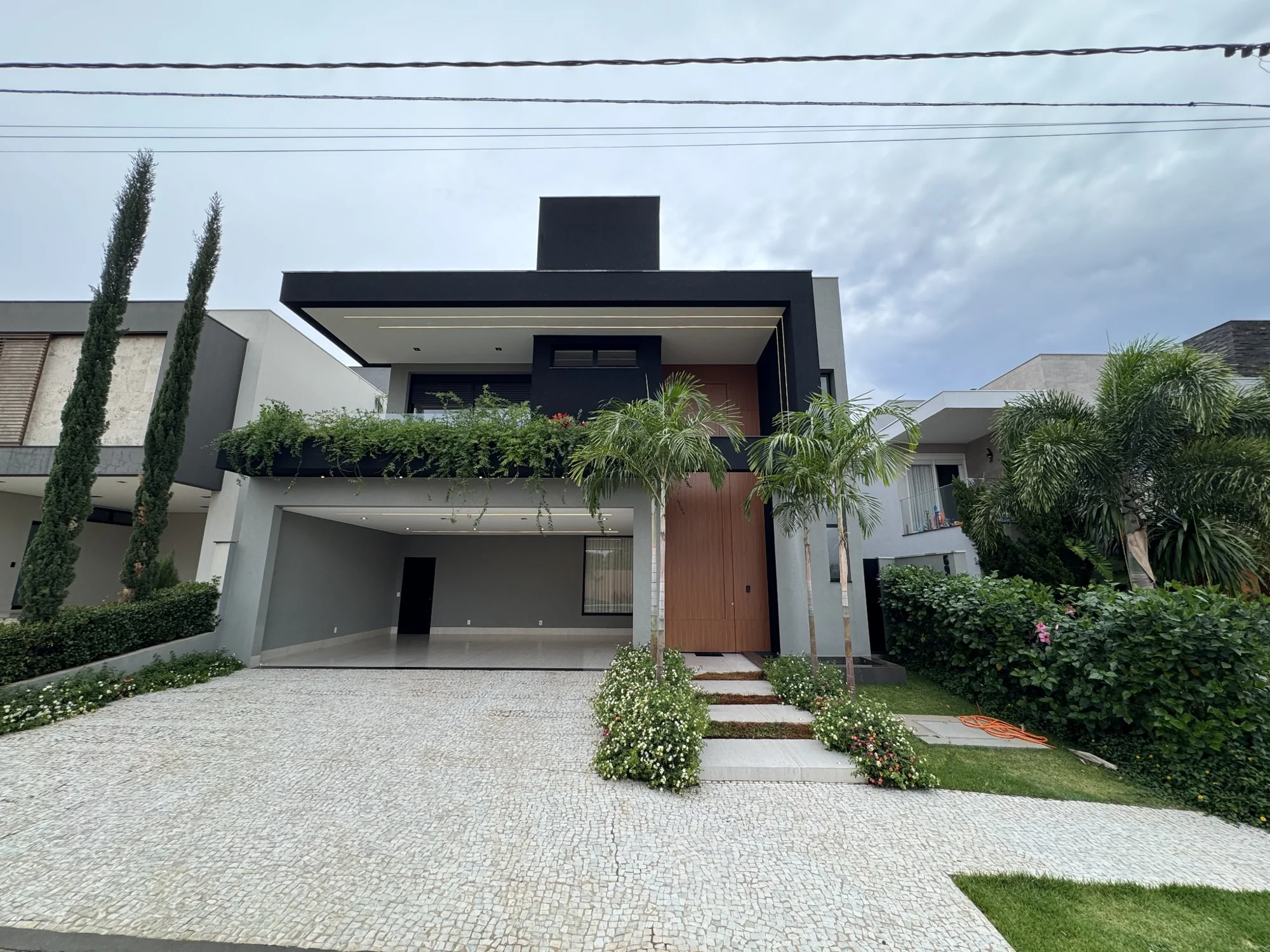 Fachada construída de residência contemporânea com pórtico escuro e paisagismo